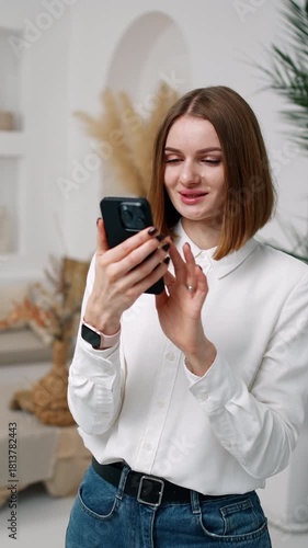Pretty brunette girl uses her phone and smiles. Man sitting at backdrop is busy with his laptop. Vertical video