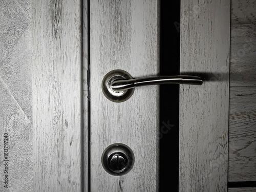 Close-up of a contemporary brushed nickel door handle and privacy lock on a white wooden door. Minimalist interior detail, modern home design.