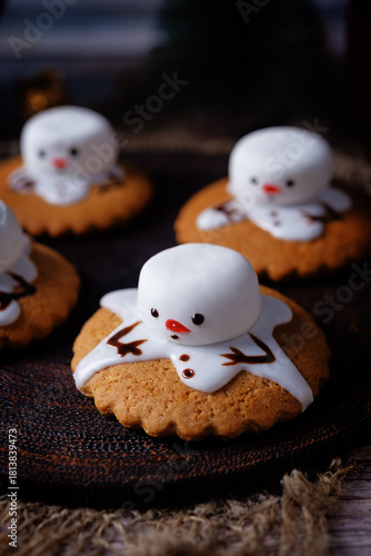 Gingerbread cookie with melting snowman topping on a wood background