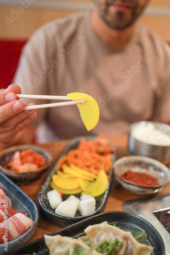 A man eats kimchi, banchan, and other Korean appetizers with chopsticks in a restaurant. Fermented food, traditional Asian meals