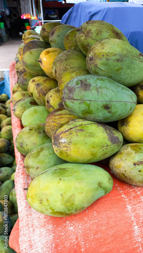 Fresh green mangoes stacked at a fruit market. Tropical produce ready for sale, natural texture and organic appearance, perfect for food, farming, and market themes.