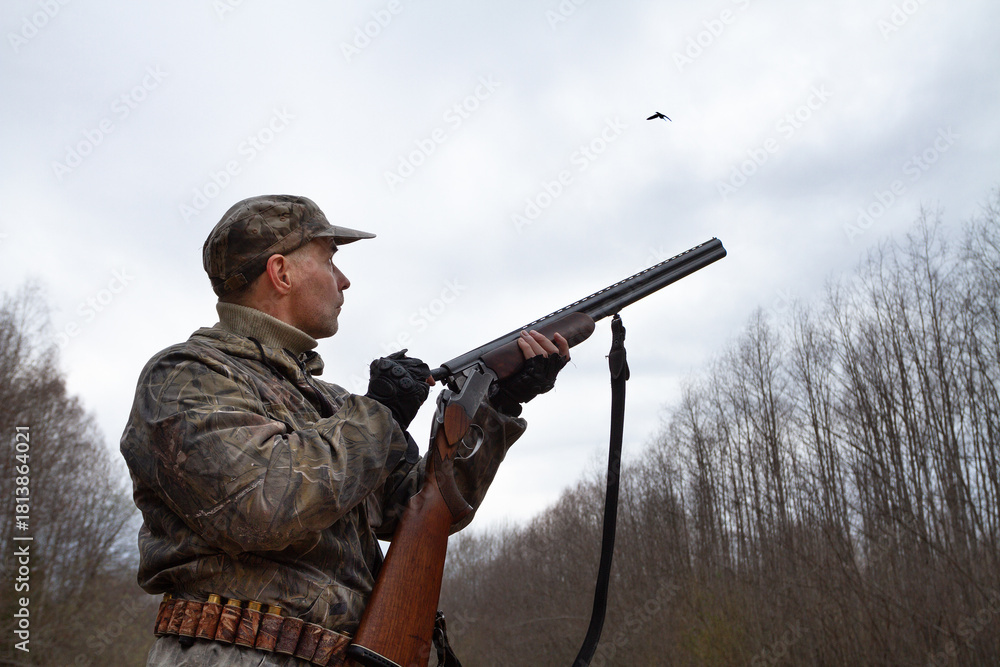 Fototapeta premium The hunter loads his shotgun and looks at the flying woodcock