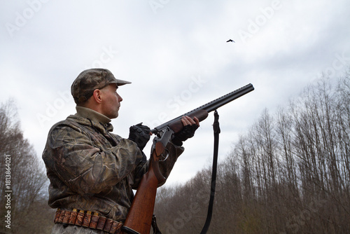 The hunter loads his shotgun and looks at the flying woodcock