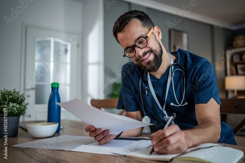 Male doctor professional studying medical paperwork and writing notes