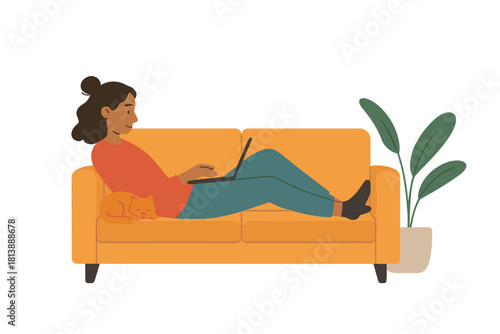 Young woman lying comfortably on a sofa working on her laptop with a sleeping cat and houseplant