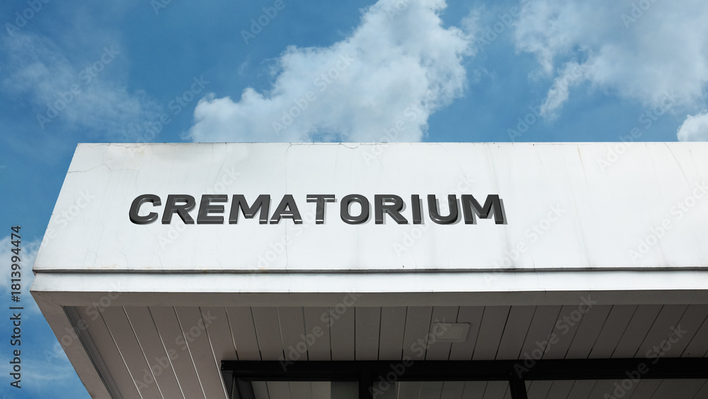Naklejka premium Crematorium word sign displayed on a building under a clear blue sky, representing funeral services, memorials, cremation, bereavement, and respectful facilities