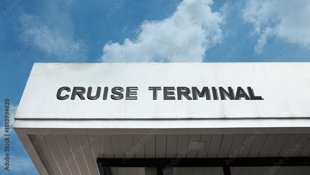 Obraz premium Cruise Terminal word sign displayed on a building under a clear blue sky, representing maritime transport, passenger services, tourism, port facilities, and travel operations
