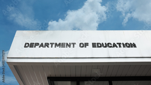 Department of Education word sign on a building under a clear blue sky, representing education, policy, learning, government services, academic development, and curriculum