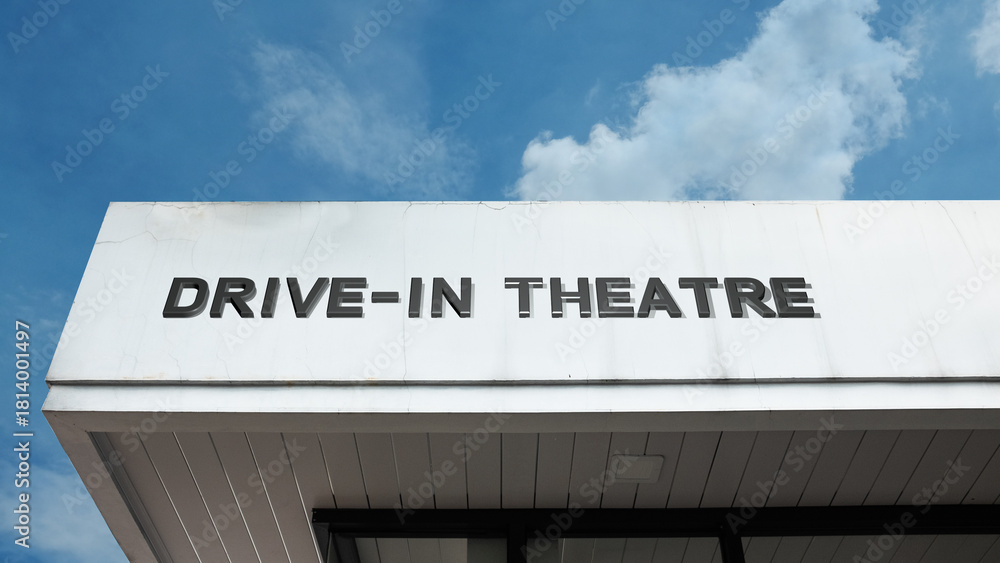 Obraz premium Drive-in theatre word sign displayed on a vintage-style building with clear blue sky, evoking nostalgia and classic outdoor cinema experience.