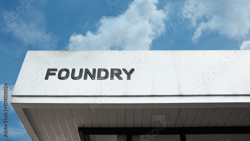 Foundry word sign displayed on a building under a clear blue sky, representing metal casting, industry, manufacturing, fabrication, and heavy production work