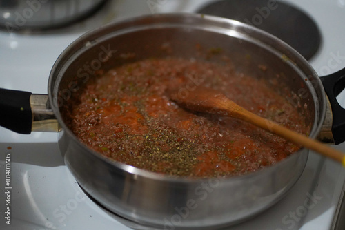 Homemade tomato meat sauce simmering in stainless steel pot on stovetop
