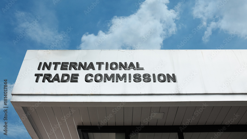 Naklejka premium International Trade Commission sign on a building against a clear blue sky, symbolizing global commerce, economic policy, trade regulation, governmental oversight, and body