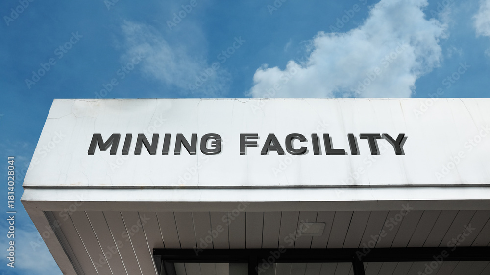 Obraz premium Mining Facility sign on a building against a clear blue sky, symbolizing resource extraction, industrial operations, mineral processing, heavy industry, and production site