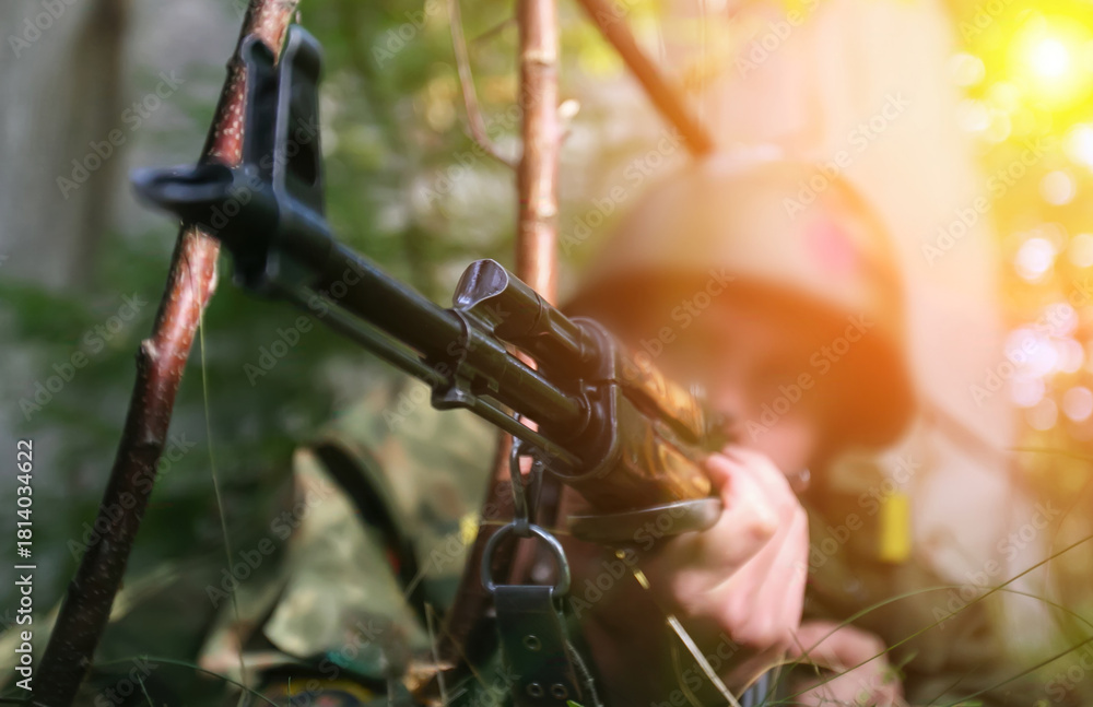 Naklejka premium Soldier aiming rifle in dense forest during military training exercise at sunset