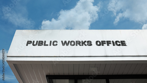 Foto Public Works Office word signage on a government building under a blue sky, symb