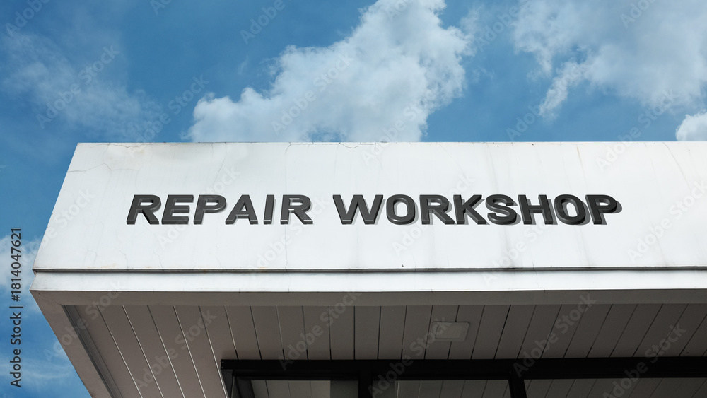 Obraz premium Repair Workshop word signage on an industrial or technical building under a blue sky, symbolizing professional maintenance, fabrication, specialized service, technical expertise, and fixing