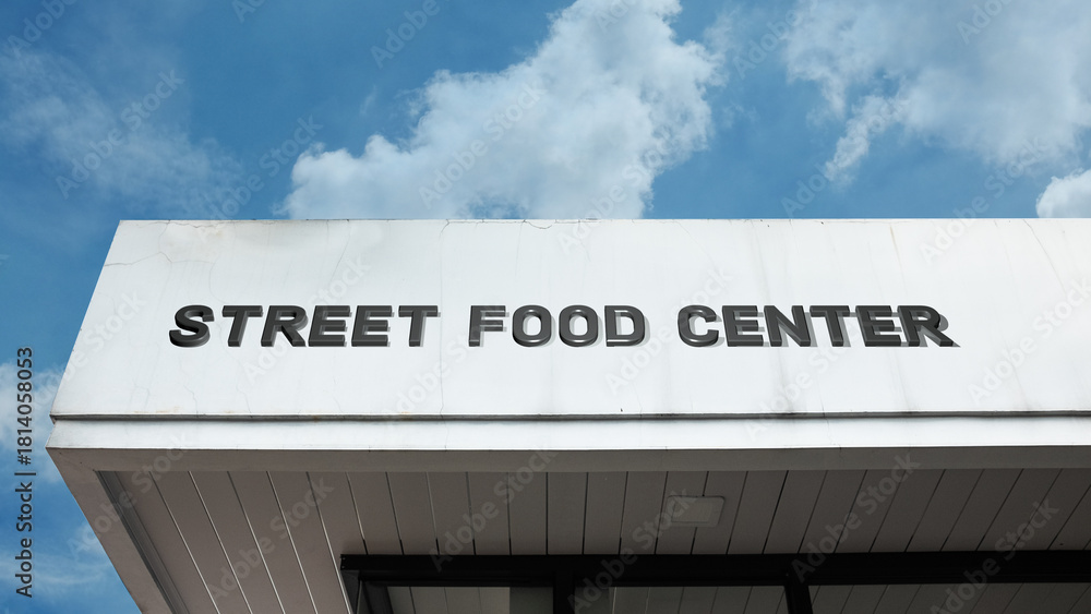 Fototapeta premium Street Food Center word signage on a commercial or public building under a blue sky, symbolizing eating, culinary culture, vendor hub, quick meals, tourism, dining, and diverse cuisine