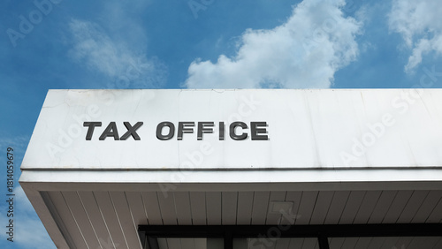Tax Office word signage on a governmental or institutional building under a blue sky, symbolizing finance, revenue, compliance, bureaucracy, government agency, audit, and fiscal regulation