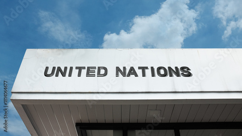 United Nations word signage on a global diplomatic building under a blue sky, symbolizing international relations, cooperation, peace, diplomacy, and global governance