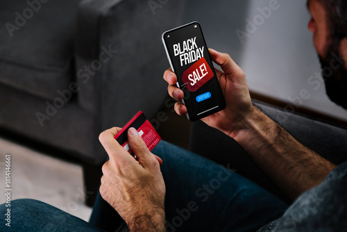 Black Friday discounts offers. Man with a credit card holding a mobile phone making a payment for online shopping.
