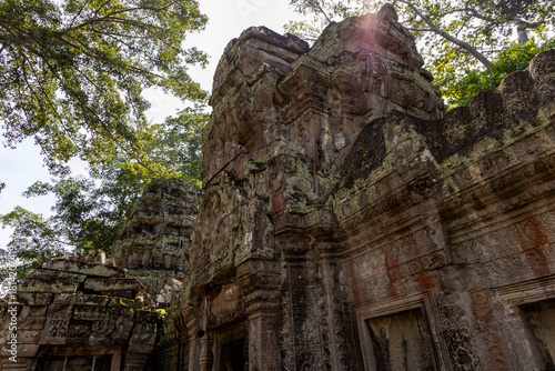 Detailed view of ancient stone structures at Ta Prohm. Intricate carvings, weathered surfaces, lush greenery
