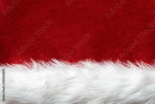 A close-up of the faux fur texture of a Santa Claus hat. Red and white Christmas background.