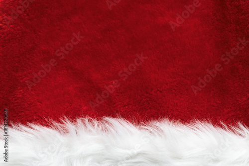 A close-up of the faux fur texture of a Santa Claus hat. Red and white Christmas background.