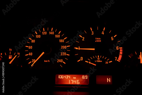 Close up of a speedometer in a car, illuminated with orange light. After edits.