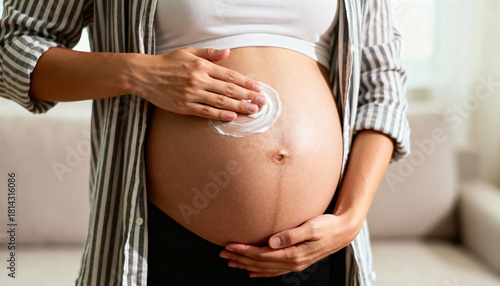 Pregnant woman applying moisturizing cream to her belly, showcasing self-care and nurturing, with a cozy indoor setting enhancing the warmth of motherhood