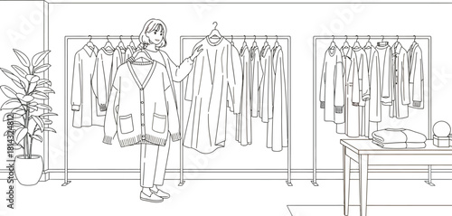 Woman selecting a cardigan from a clothing rack in a minimalist fashion store