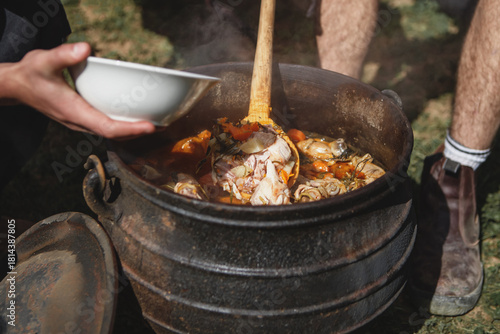 Cooking stew in cast iron cauldron outdoors