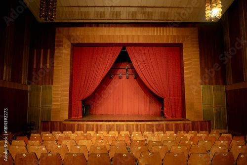 an old empty theater auditorium with seats and a dimly lit stage