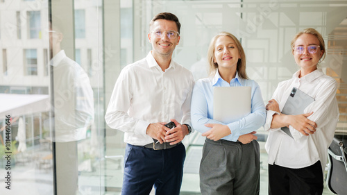 Three professionals pose in a modern office space