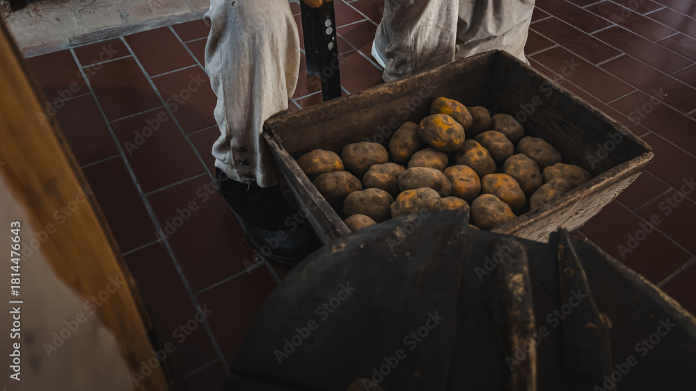 Naklejka premium Wooden Box Full of Dirty Potatoes, Scenography Detail with the Figure of a Soldier in Uniform in the Historic Kitchen