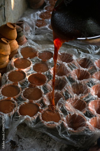 Rural Industry: Worker Pouring Date Syrup into Terracotta Containers in Bangladesh