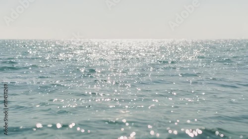 Gentle waves shimmer with sunlight reflecting across a serene expanse of water
