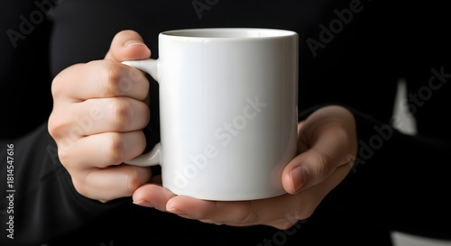 Person holding a white mug in front of a black background