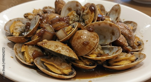 A close-up of a white plate filled with delicious stir-fried clams in a savory brown sauce.