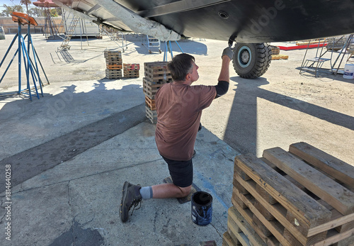  Man applying antifouling paint on hull.