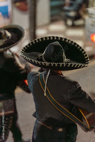 Mexican Mariachi Guitarist in Sombrero and Charro Suit Seen from Behind on City Street at Night