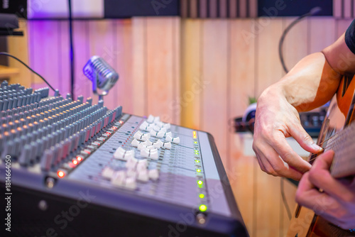 close up male musician hands playing acoustic guitar in home studio, recording concept.