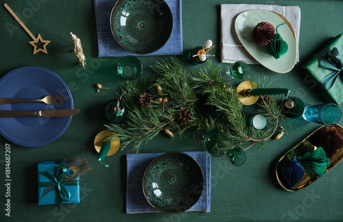 Christmas celebration table settings with winter holiday decorations on the green linen cloth.