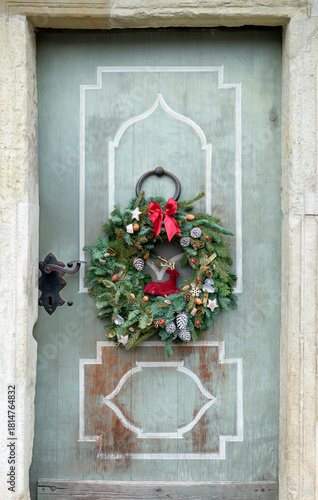 Spruce Advent christmas wreath on the wooden door in the evening light.
