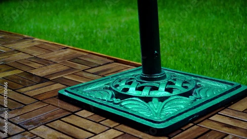 Composition of wooden parquet and grass in an outdoor setting during rainy weather. Focus and depth of field are selective. A romantic rainy landscape in the garden.