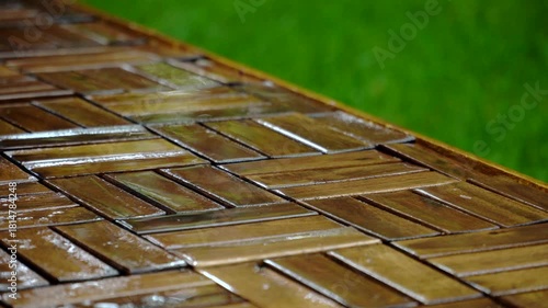 Composition of wooden parquet and grass in an outdoor setting during rainy weather. Focus and depth of field are selective. A romantic rainy landscape in the garden.