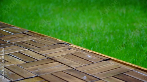 Composition of wooden parquet and grass in an outdoor setting during rainy weather. Focus and depth of field are selective. A romantic rainy landscape in the garden.