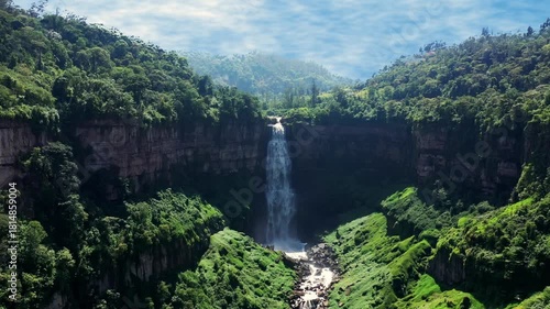 Aerial drone view of tall waterfall plunging into lush green canyon in Andes mountains near Bogota Colombia
