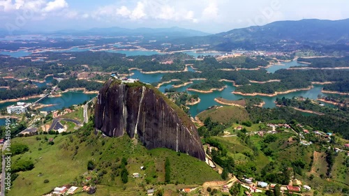 Cinematic drone flight rising over the Rock of Guatape and blue lake landscape near Medellin Colombia