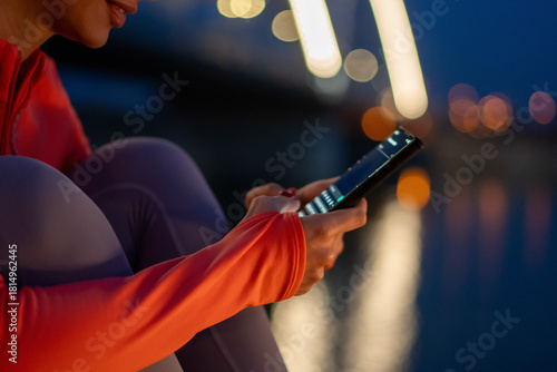 Woman using smartphone at night with blurred city lights in background