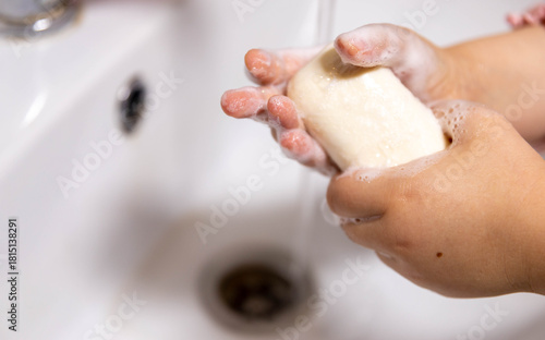 Children's hands in soap suds in a blue bath. Baby detergent, hygiene.